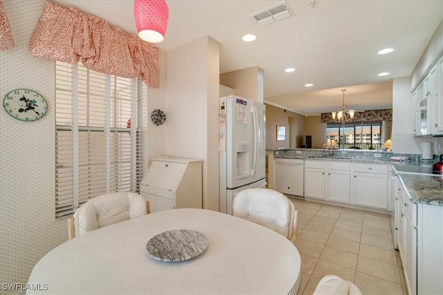 kitchen with white appliances, an inviting chandelier, white cabinets, decorative light fixtures, and kitchen peninsula