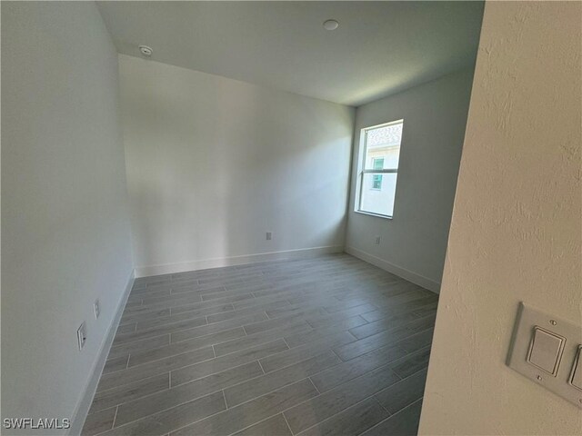 unfurnished room with dark wood-type flooring