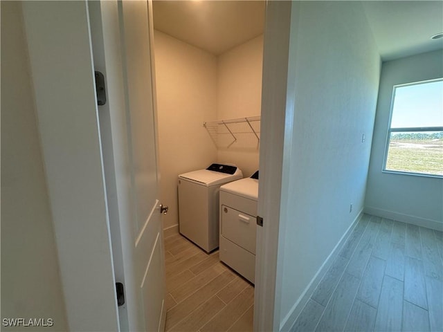 clothes washing area with washer and dryer and light hardwood / wood-style floors