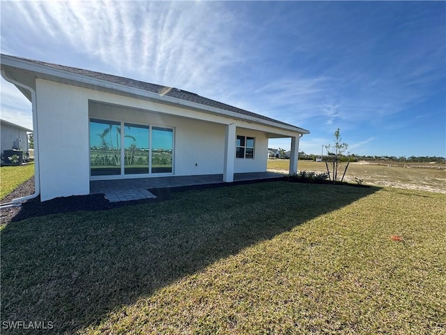 back of property with a yard and a patio