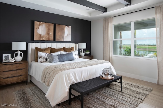 bedroom with beam ceiling and hardwood / wood-style floors