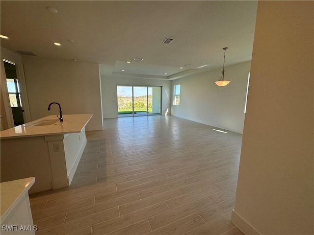 kitchen featuring light wood-type flooring, open floor plan, visible vents, and a sink