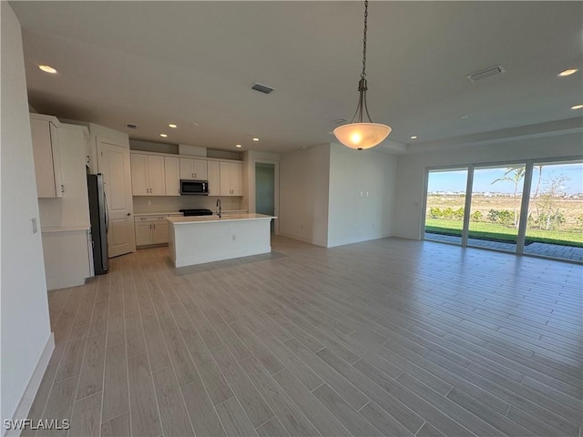 kitchen with light wood finished floors, stainless steel appliances, light countertops, and open floor plan