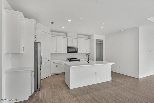 44488 Little Blue Heron Way, Punta Gorda, FL 33982 - kitchen with stainless steel appliances, recessed lighting, a sink, white cabinets, and light wood finished floors