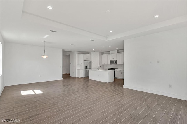 44488 Little Blue Heron Way, Punta Gorda, FL 33982 - unfurnished living room with wood finished floors, a sink, recessed lighting, a tray ceiling, and baseboards