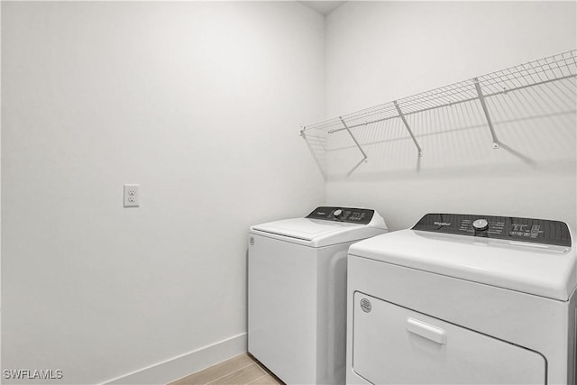 44488 Little Blue Heron Way, Punta Gorda, FL 33982 - laundry area featuring washing machine and dryer, baseboards, and light wood-style floors