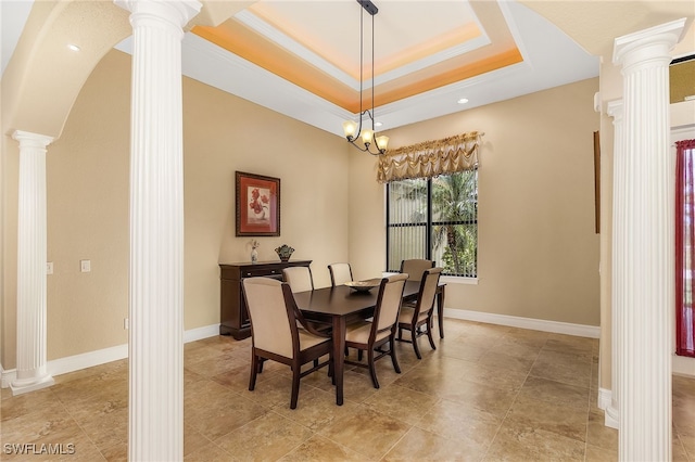 dining space featuring decorative columns, a tray ceiling, a chandelier, and ornamental molding