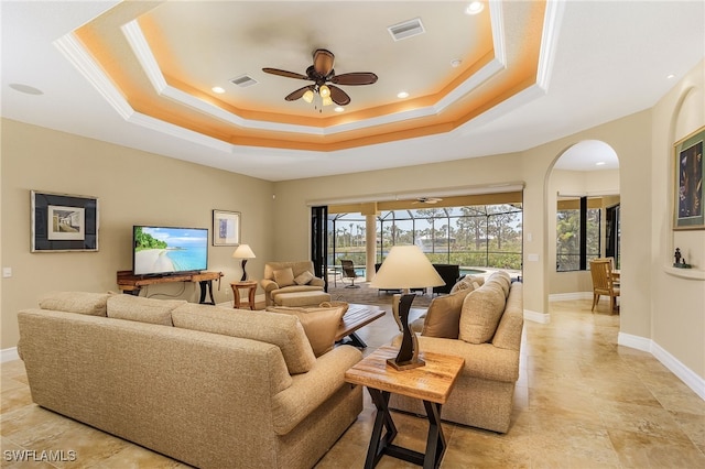 living room featuring a raised ceiling and ceiling fan