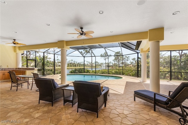 view of swimming pool featuring a patio, glass enclosure, ceiling fan, and a wet bar