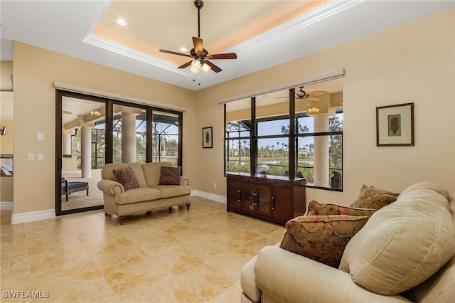 living room featuring a tray ceiling, ceiling fan, and crown molding