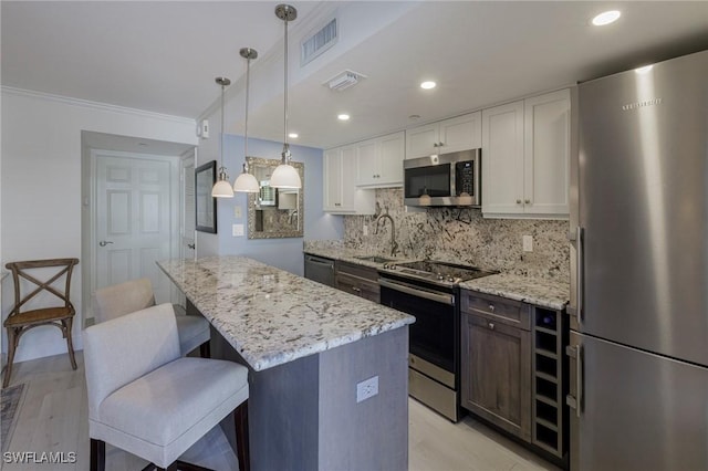 kitchen with pendant lighting, sink, light hardwood / wood-style flooring, appliances with stainless steel finishes, and white cabinetry