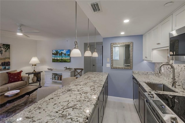 kitchen with pendant lighting, sink, appliances with stainless steel finishes, light stone counters, and white cabinetry