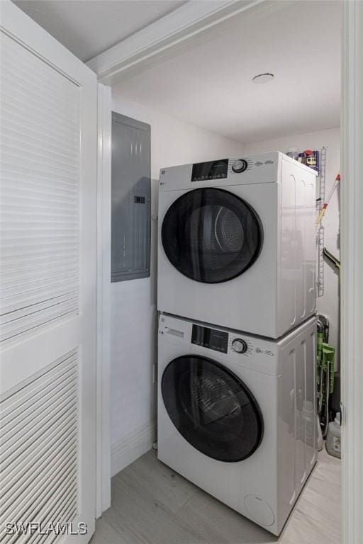 laundry room featuring light wood-type flooring, stacked washer and dryer, and electric panel