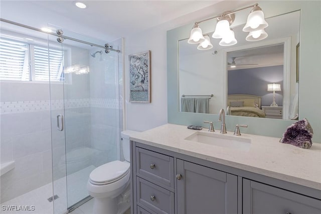 bathroom featuring a shower with door, vanity, and toilet