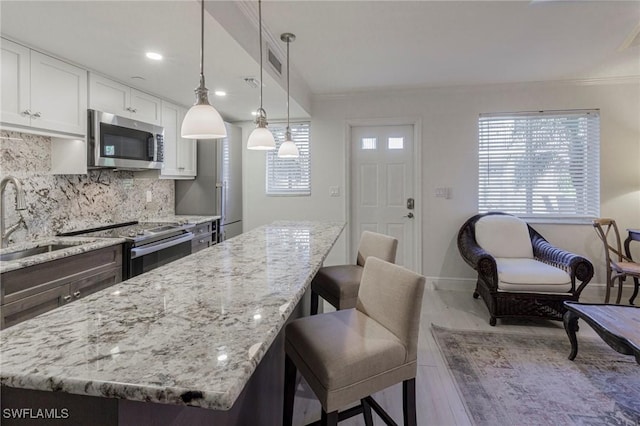 kitchen featuring pendant lighting, sink, hardwood / wood-style flooring, appliances with stainless steel finishes, and white cabinetry