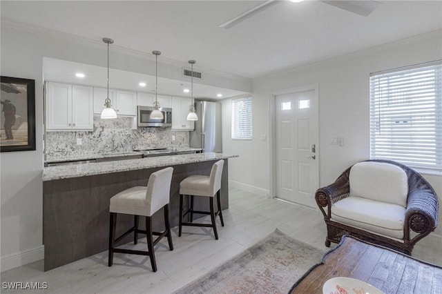 kitchen with pendant lighting, white cabinets, light hardwood / wood-style flooring, light stone countertops, and stainless steel appliances