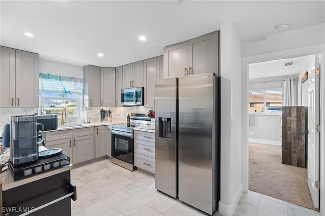 kitchen featuring light carpet, appliances with stainless steel finishes, backsplash, and plenty of natural light