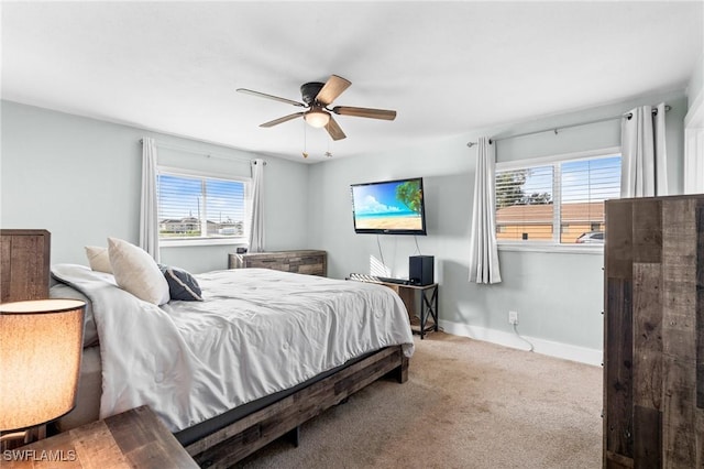 bedroom featuring ceiling fan, light colored carpet, and multiple windows