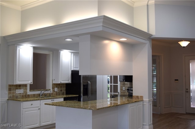 kitchen featuring white cabinetry, kitchen peninsula, tasteful backsplash, and dark stone countertops