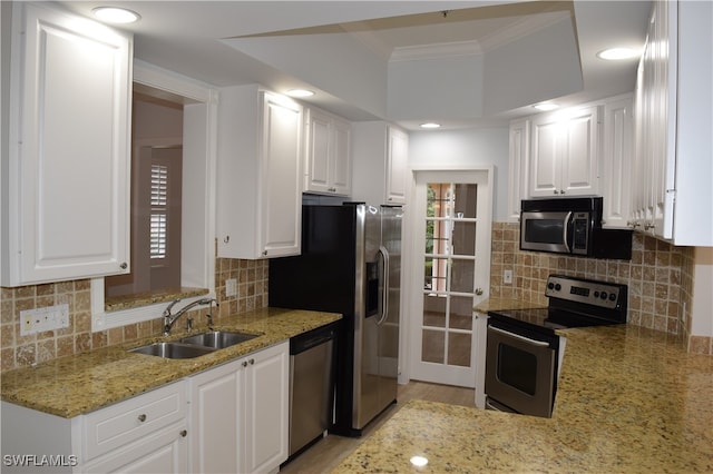 kitchen with appliances with stainless steel finishes, sink, white cabinets, crown molding, and light stone countertops