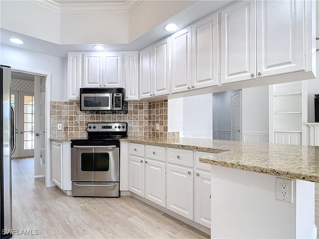 kitchen featuring crown molding, appliances with stainless steel finishes, light stone counters, white cabinets, and kitchen peninsula