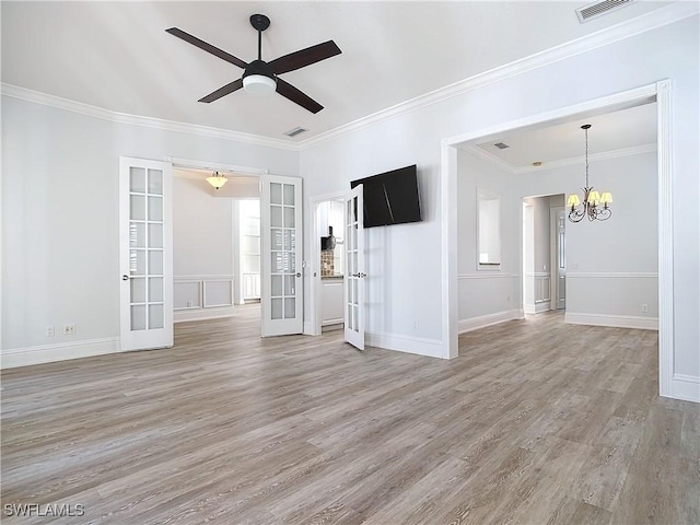 spare room featuring hardwood / wood-style flooring, crown molding, ceiling fan with notable chandelier, and french doors