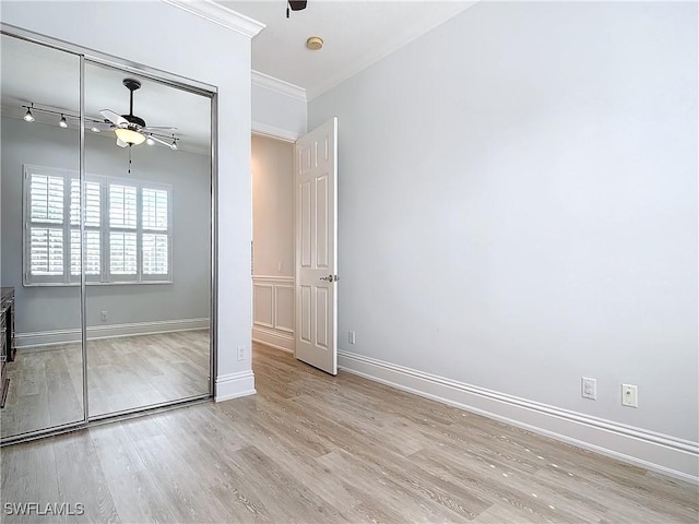 unfurnished bedroom with light hardwood / wood-style floors, ornamental molding, a closet, and ceiling fan