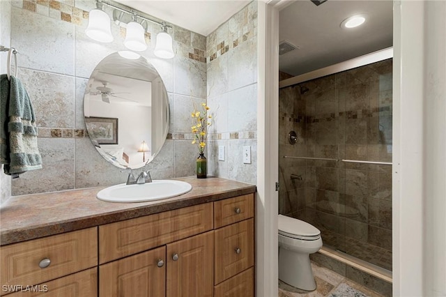 bathroom featuring ceiling fan, a shower with shower door, tile walls, and toilet