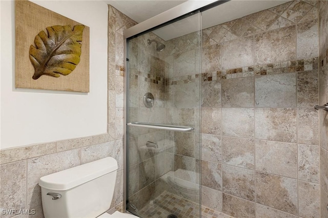 bathroom featuring toilet, tile walls, and walk in shower