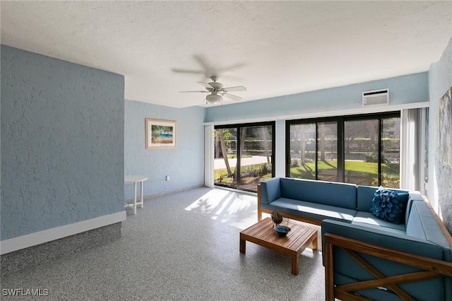 living room featuring ceiling fan and a textured ceiling