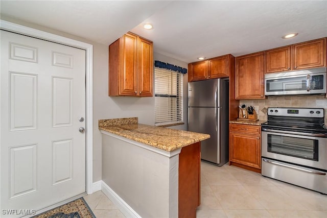 kitchen with tasteful backsplash, light tile patterned flooring, light stone counters, kitchen peninsula, and stainless steel appliances