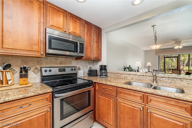 kitchen featuring light stone countertops, sink, pendant lighting, and appliances with stainless steel finishes