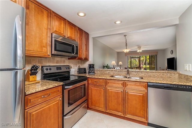 kitchen with ceiling fan, sink, light stone counters, kitchen peninsula, and appliances with stainless steel finishes