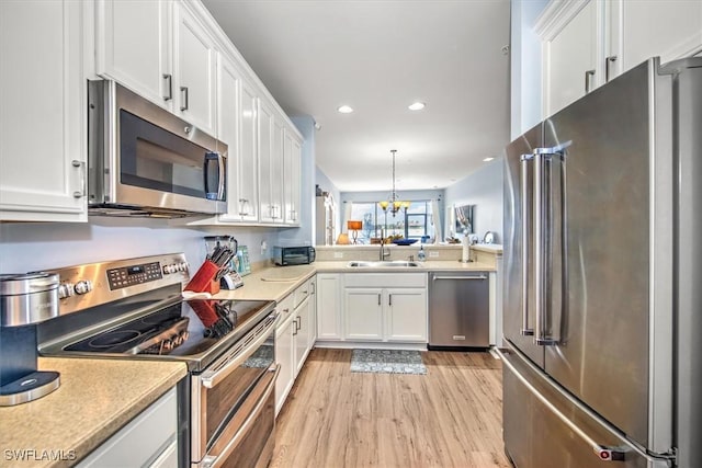 kitchen featuring decorative light fixtures, white cabinetry, sink, and appliances with stainless steel finishes