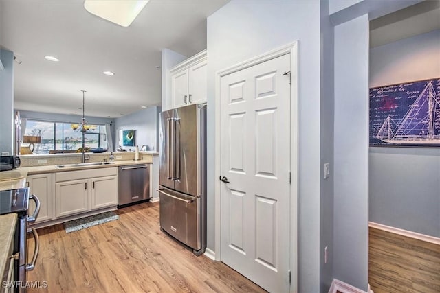 kitchen featuring sink, white cabinets, pendant lighting, and appliances with stainless steel finishes