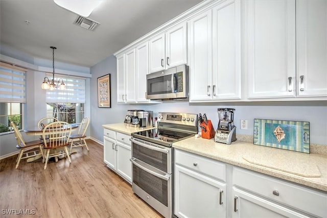 kitchen featuring white cabinetry, stainless steel appliances, light stone counters, light hardwood / wood-style floors, and decorative light fixtures