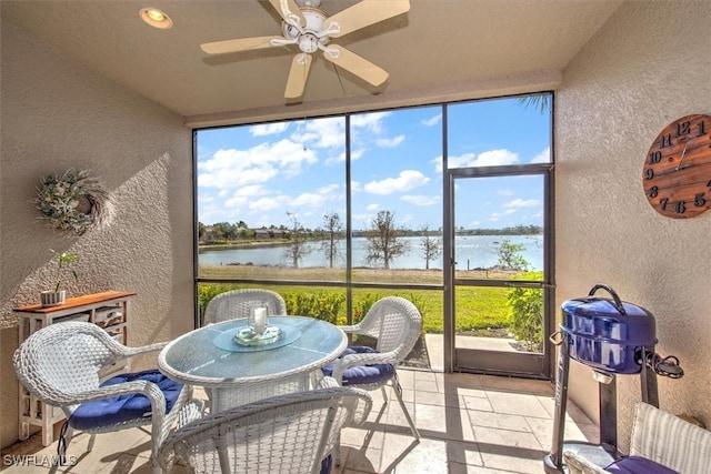 sunroom featuring ceiling fan and a water view