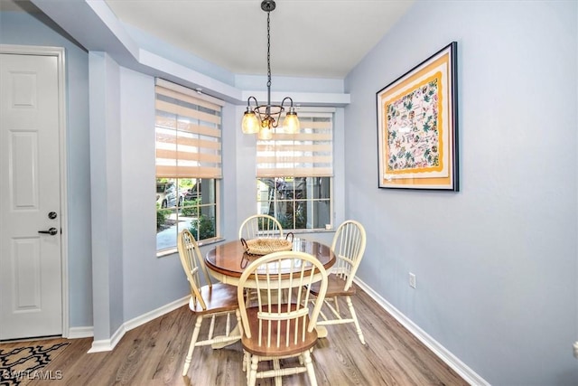 dining space with wood-type flooring and an inviting chandelier