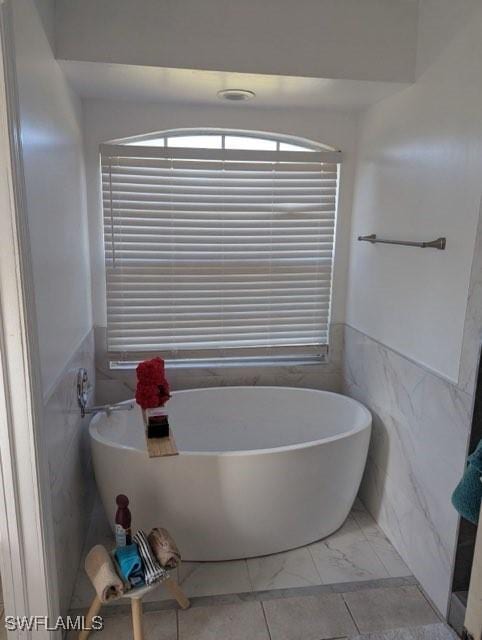 bathroom with tile walls and a tub