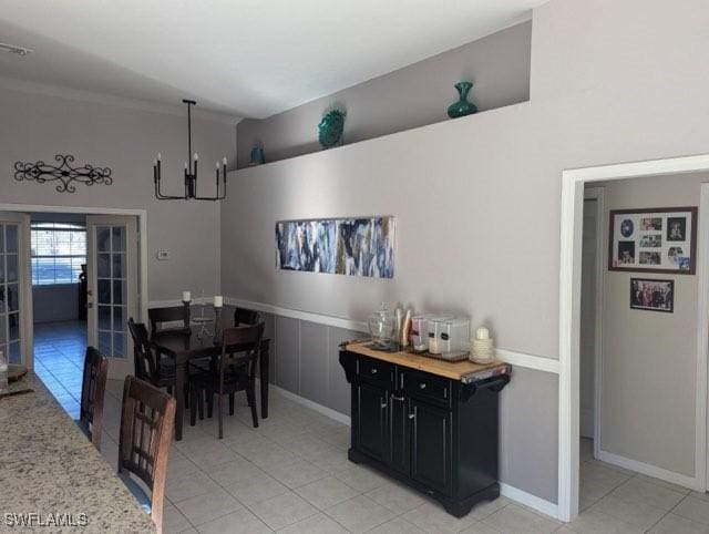 dining area with french doors, light tile patterned floors, ornamental molding, and a notable chandelier