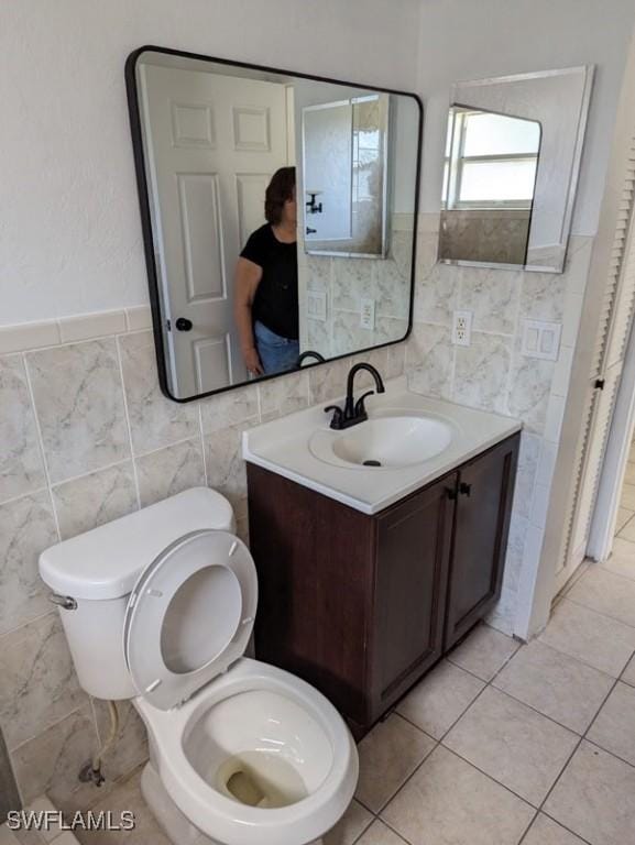 bathroom featuring vanity, toilet, and tile walls