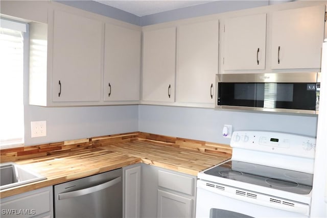 kitchen featuring white cabinets, butcher block counters, and appliances with stainless steel finishes