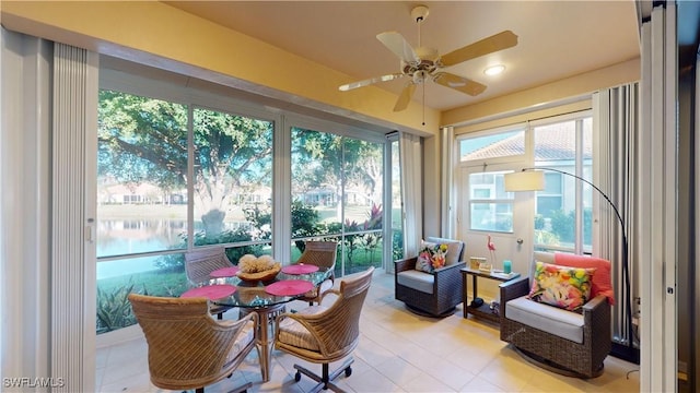 sunroom / solarium featuring ceiling fan and a water view