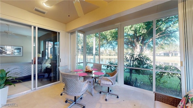 sunroom / solarium featuring ceiling fan and a water view