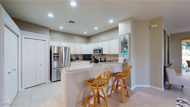 kitchen with white cabinetry, tasteful backsplash, a kitchen breakfast bar, kitchen peninsula, and appliances with stainless steel finishes