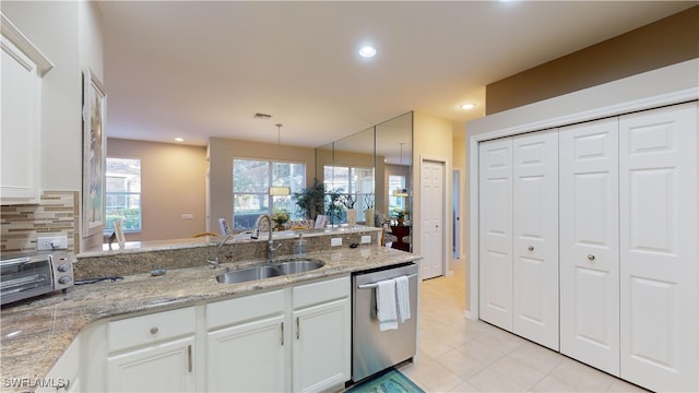 kitchen with light stone countertops, stainless steel dishwasher, sink, white cabinetry, and hanging light fixtures