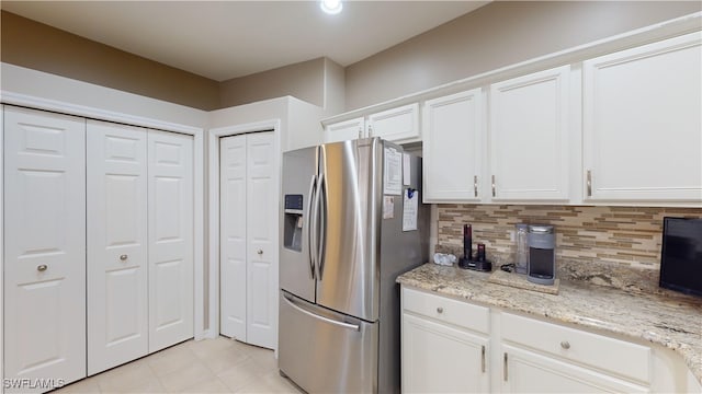 kitchen featuring decorative backsplash, stainless steel refrigerator with ice dispenser, white cabinetry, and light stone counters