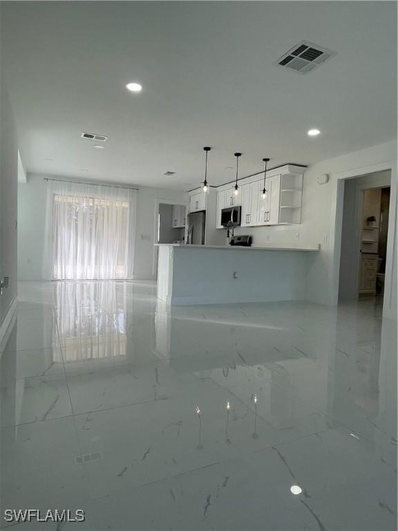 kitchen with kitchen peninsula, appliances with stainless steel finishes, white cabinetry, and pendant lighting