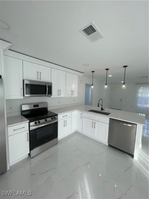 kitchen featuring hanging light fixtures, kitchen peninsula, sink, and appliances with stainless steel finishes