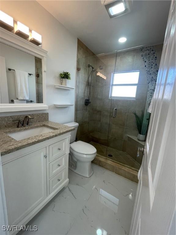 bathroom with vanity, toilet, and a shower with door